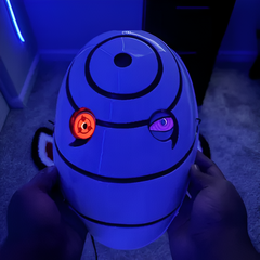 Máscara blanca de Obito de la 4.ª Guerra Ninja con los ojos iluminados, sujeta con las manos